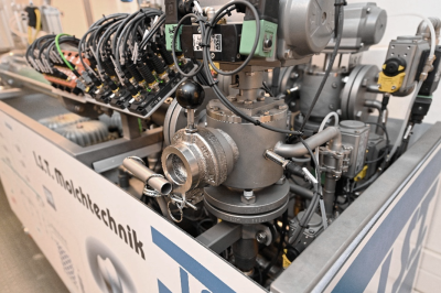 Eine Nahaufnahme einer industriellen Ventilkomponente mit einem Hebel, umgeben von Metallrohren und elektrischen Kabeln mit Anschl&uuml;ssen. Das Ger&auml;t tr&auml;gt die Beschriftung "I.S.T. Molchtechnik".