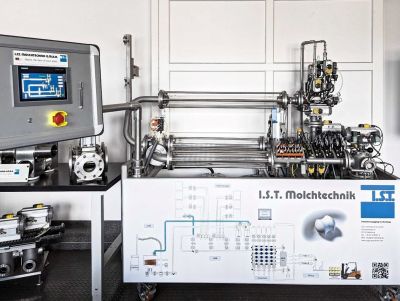 Ein komplexes industrielles System mit Edelstahlrohren, Ventilen und einem Steuerungsdisplay von I.S.T. Molchtechnik, das auf einem Whiteboard mit einem schematischen Diagramm und Markierungen wie "Tank Storage", "Manifold" und "Filling" dargestellt ist.